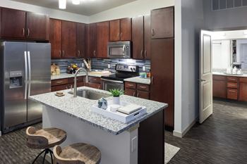 A kitchen with a granite countertop and wooden cabinets at Regatta Sloans Lake Apartments, Colorado